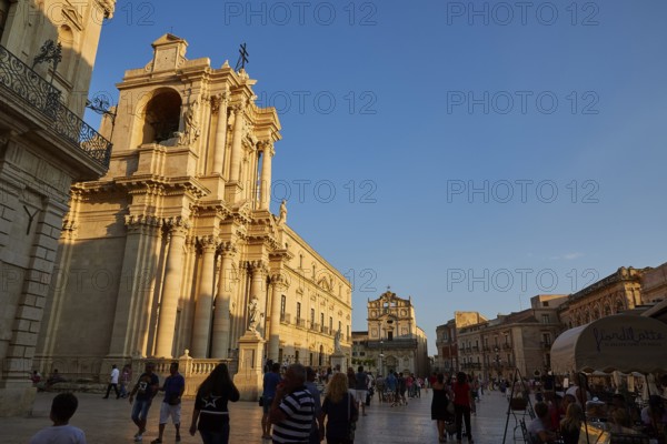 Cathedral of Syracuse, people strolling by an impressive cathedral on a square at sunset, Ortigia Island, Isola di Ortigia, historic old town, Syracuse, Sicily, Italy