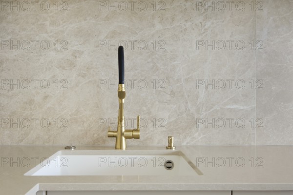 Modern kitchen faucet design with gold finish and minimalist aesthetic in bright interior space