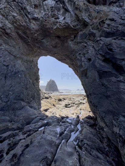 Large rock with a hole and people in the foreground, Hole in The Wall, Rialto Beach, Olympic National Park, Washington, USA, North America