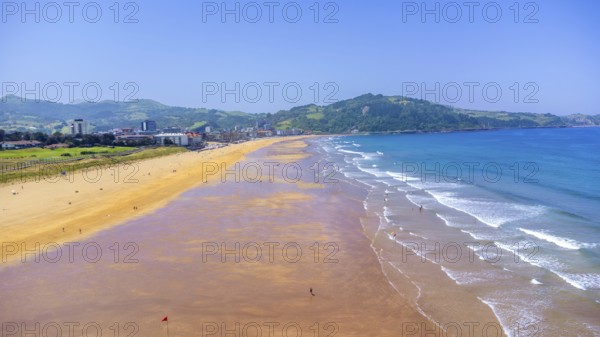 Aerial view of zarautz beach and town on a sunny summer day, showing the golden sand, blue water, and green hills of gipuzkoa, basque country, spain