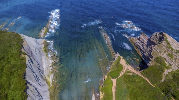 Breathtaking aerial view of the unique flysch rock formations along the coast of zumaia in the basque country, showcasing the stunning contrast of turquoise water and layered cliffs, Spain.