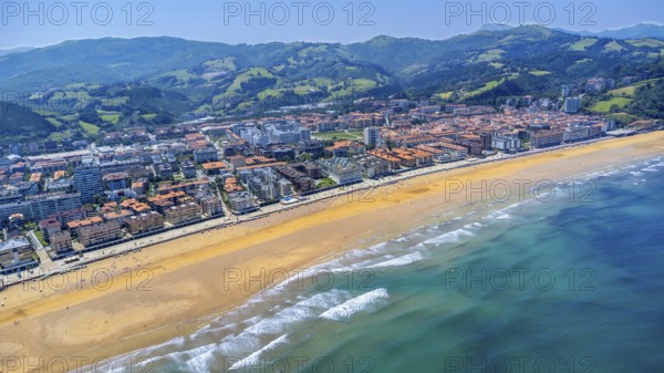 Aerial view of zarautz, gipuzkoa, showcasing the golden sands meeting the turquoise waves of the bay of biscay on a sunny summer day, Spain.