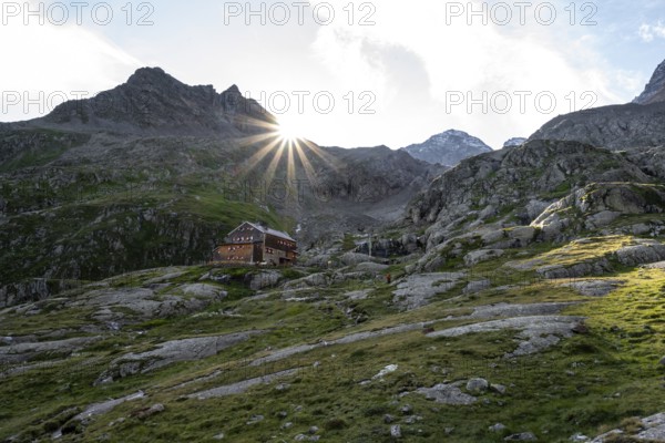 Mountain hut Elberfelderhütte in front of a rocky mountain landscape, sun star in the morning, in the upper Gössnitz valley, Wiener Höhenweg, Schober group, Hohe Tauern National Park, Carinthia, Austria