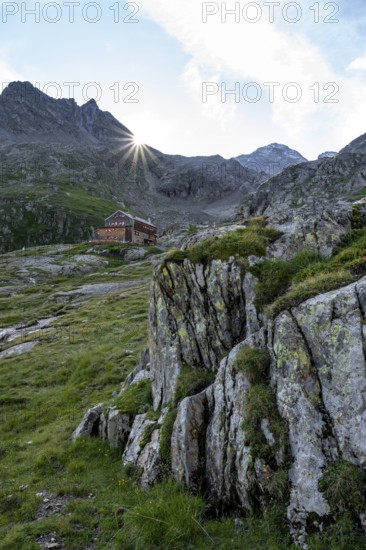 Mountain hut Elberfelderhütte in front of a rocky mountain landscape, sun star in the morning, in the upper Gössnitz valley, Wiener Höhenweg, Schober group, Hohe Tauern National Park, Carinthia, Austria