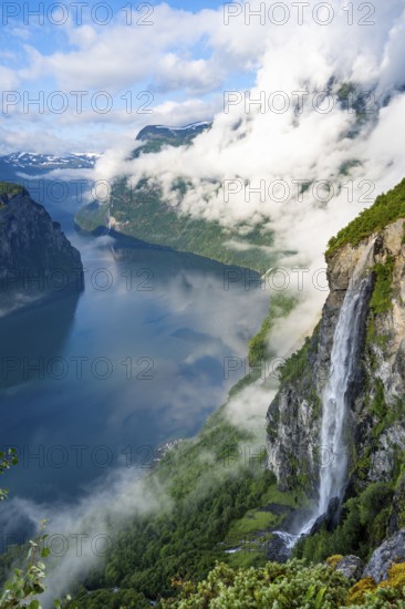 Gjerdefossen waterfall, at Ørnesvingen viewpoint, atmospheric clouds over the fjord in the morning light, at Geirangerfjord, near Geiranger, Møre og Romsdal, Norway