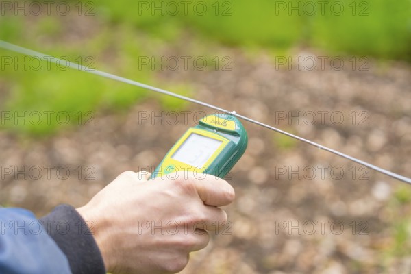 Hands holding a device for an electrical measurement on a wire, Waldweide Gechingen, compensation project for the Hermann Hesse railway to create ecological habitats for endangered species, district of Calw, Germany
