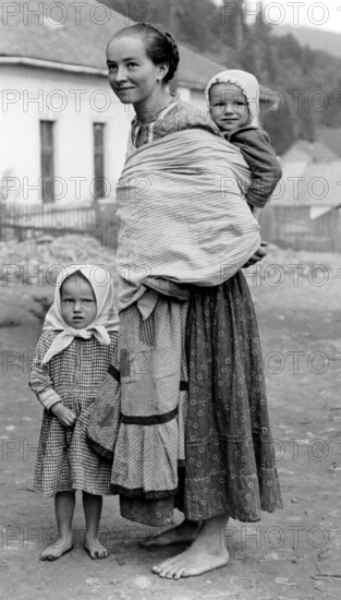 Farmer's woman and children, 1930s, A woman with two children in traditional dress on a dusty road, Historical photo