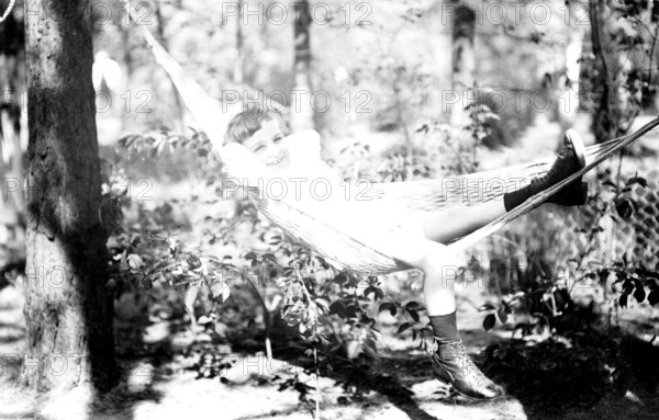 Boy lying in hammock, 1920s, Smiling child lying in a hammock in the forest, Historical photo