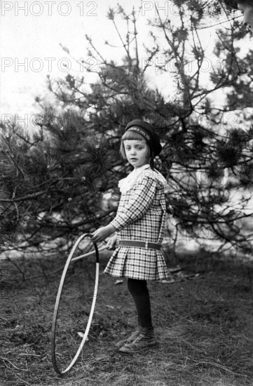 Tyre toy, 1920s, A young girl with a hula hoop stands next to a tree and looks curiously, Historical photo