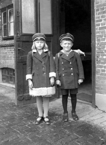 Brother sister pupil, 1920s, Two children in old-fashioned clothes stand seriously in front of an entrance, Historical photo