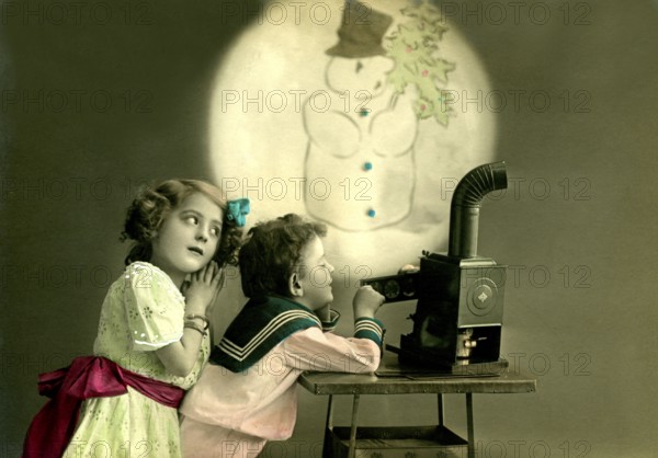 Children's slide projector snowman, 1912, Two children watching a snowman projection, nostalgic atmosphere with an old projector, historical photo