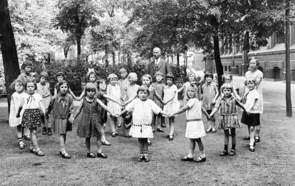 School class girls teachers schoolyard, 1920s, A group of children holding hands on an outdoor playground, Historical photo