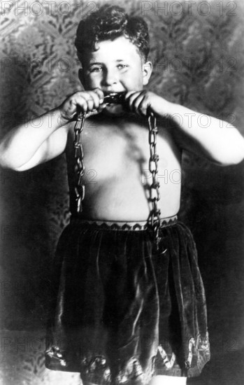 Strong boy 1920, A boy bites into a chain as if to demonstrate strength, Historical photo