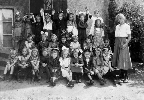 Group of girls in the 1930s, ca. 1930, A large group of children and a teacher are happy and posing outside, historical photo