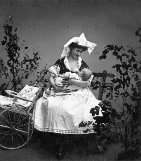 Motherly love, mother breastfeeding baby, 1930s, mother breastfeeding baby next to a cart, black and white photo with loving feeling, historical photo