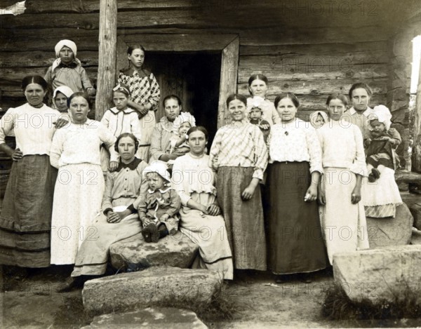 Large family in the countryside, 1920s, Group of woman and children in front of a wooden house, Black and white photo with traditional style, Historical photo