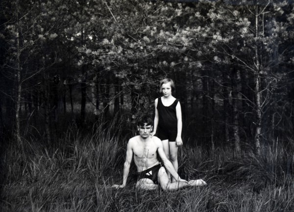 Brother and sister in swimming costumes, 1930s, Two people in swimming costumes in a forest, one sitting, the other standing, looking serious, Historical photo