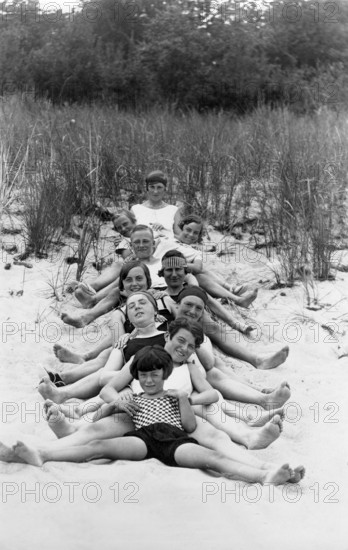 Group on the beach, 1930s, children in black and white swimming costumes smiling on the sand and enjoying the summer day, historical photo