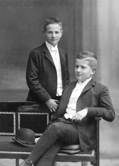 Two boys in suits, 1930s, Two boys in elegant suits pose confidently, one standing the other sitting, Historical photo