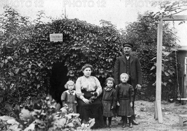 Family photo in the garden, 1930s, Family portrait with parents and three children in front of a pergola in the garden, Historical photo