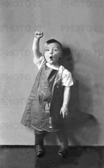 Working class, child raises fist, 1920s, A boy wears an apron and raises his fist energetically, Historical photo