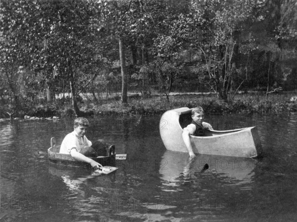Two boys rowing in funny boats, 1930s, Two men rowing in self-made boats on a body of water, Historical photo