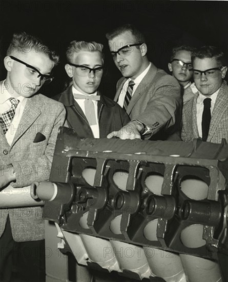Pupil looks bored while teacher explains, 1950s, group of men examining a technical model. All wearing suits and looking with interest at the object, historical photo