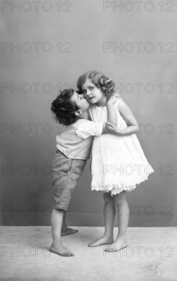 The first kiss, 1930s, Two children in an intimate embrace, Boy gives girl a kiss on the cheek, Historical photo