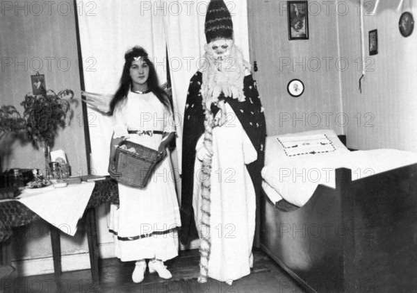 Christmas angels and St Nicholas, 1930s, A dressed-up couple stands in a festively decorated room, Historical photo