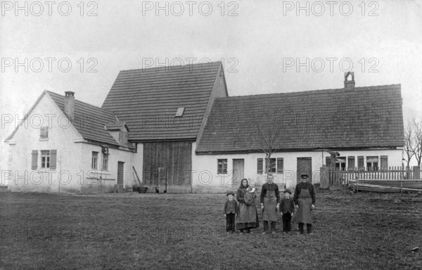 Farmers, family in front of the house, 1920s, Family posing in front of a large rural farmhouse taken on a cloudy day, Historical photo