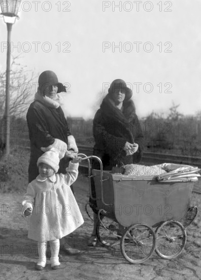 Two woman with pram and child, 1920s, Two woman and a child standing next to a pram, all in winter clothes, Historical photo