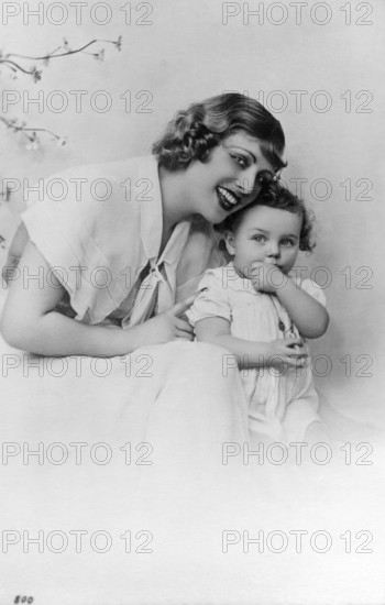 Mother with child, 1930s, Woman and small child sitting next to each other and laughing in a studio portrait, historical photo