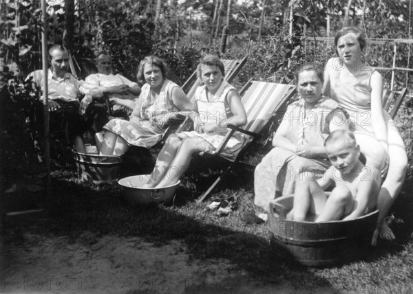 Hot summer in the garden, 1930s, people sitting in a garden and cooling off in containers filled with water, historical photo