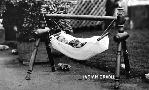 Baby hammock cradle, 1930s, A baby lies in a hanging cradle in the garden, surrounded by plants, Historical photo