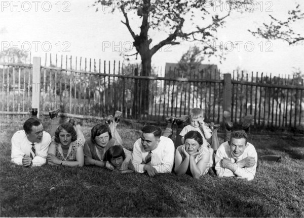 Large family lying in a row in the grass, 1930s, A group of people lying relaxed in the meadow on a sunny day, Historical photo