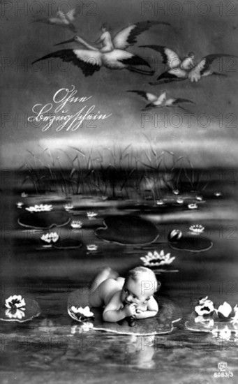 Baby lying on a leaf, 1910, A baby lies on a water lily among flying storks in a surreal dreamscape, Historical photograph