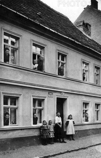 People looking out of windows, 1920, people in a house looking out of windows and standing outside, historical photo