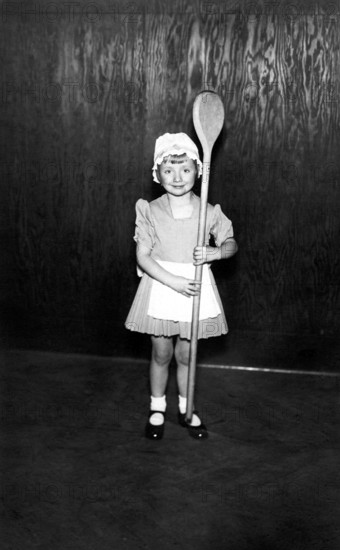 Girl with a large wooden spoon, 1930, A little girl in a costume proudly holds an oversized wooden spoon, Historical photo