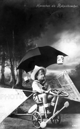 Boy with strange vehicle, 1900, A boy sits on a tricycle, holding an umbrella in a surreal-looking black and white scene, Historical photograph