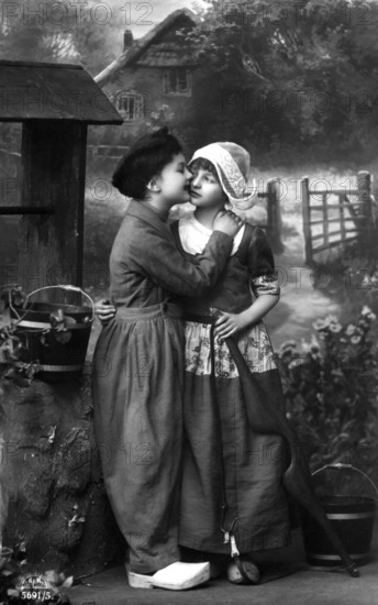 Boy kissing girl, 1920, Two children in old-fashioned clothes in front of a house in the country, Historical photo