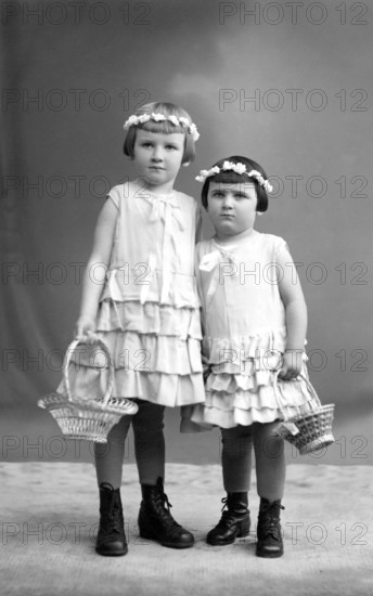 2 girls with wreaths of flowers, 1910, Two girls in dresses with baskets of flowers pose in a studio, Historical photo