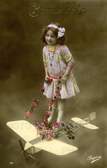 Girl with aeroplane, 1910, Girl in a purple dress posing with a toy aeroplane and flowers, Historical photo
