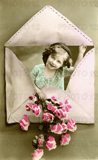 Child in an envelope, 1910, Girl looking through a heart-shaped envelope and holding flowers, historical photo