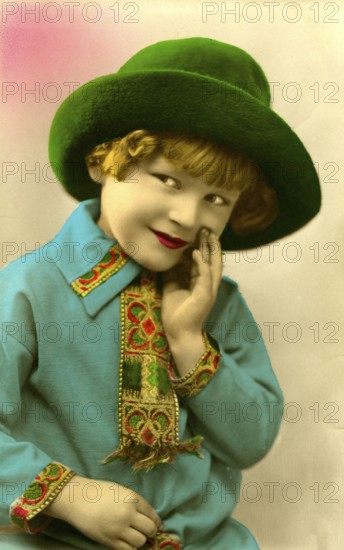 Girl with green hat, 1920, boy in green hat and blue shirt smiling and looking to the side, historical photo