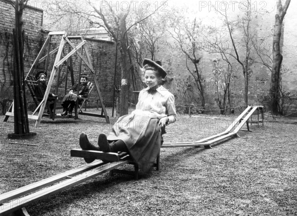 Girl on playground, 1910, Girl on a swing in an old courtyard with trees and a swing, historical photo