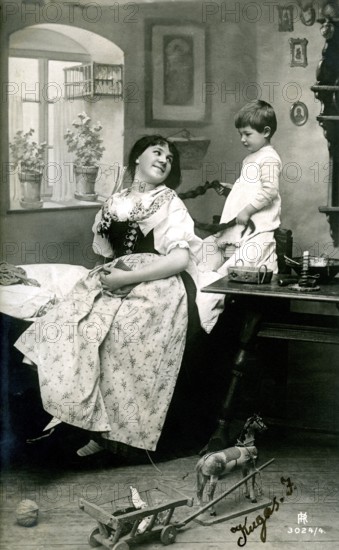 Child playing with mum's hair, 1920, A woman and a boy are inside, surrounded by toys, in a nostalgic black and white picture, Historical photo