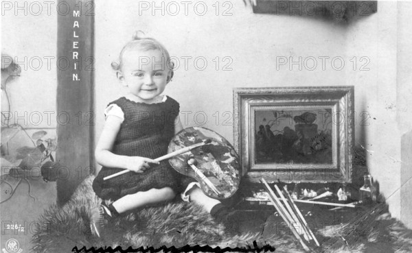 Painting, Painting, Art, Culture, Girl, Infant, Child, People, Single, Sitting, Landscape, 1910s, A baby with a colour palette and brush is sitting next to a painting, the word 'paintress' can be seen, Historical photo