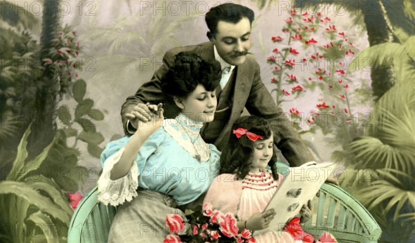 Small family, 1910s, An elegant family in a garden reading a book together, Historical photo