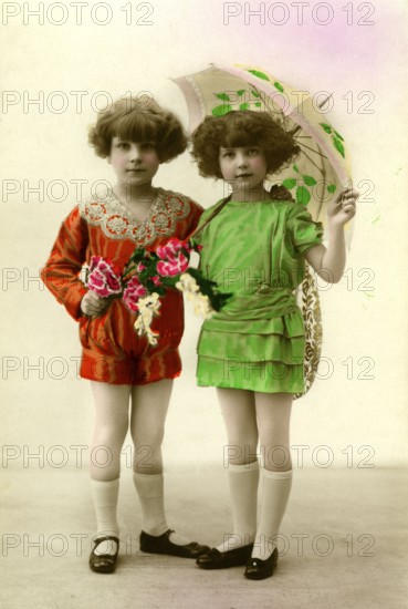 Two girls with umbrellas, 1930s, Twin girls in colourful clothes and umbrellas pose in a studio, Historical photo