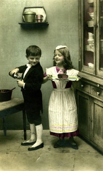 Boy and girl as servants, 1920s, A boy and a girl playing in an old kitchen with apple juice and crockery, Historical photo
